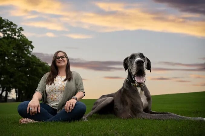 Mulher com cachorro grande em gramado