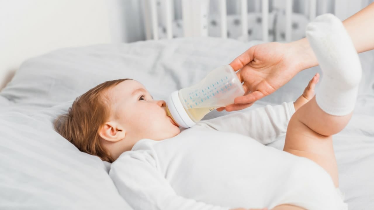 Adulto dando mamadeira para criança