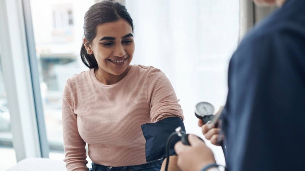 Médica medindo a pressão arterial de uma paciente sorrindo