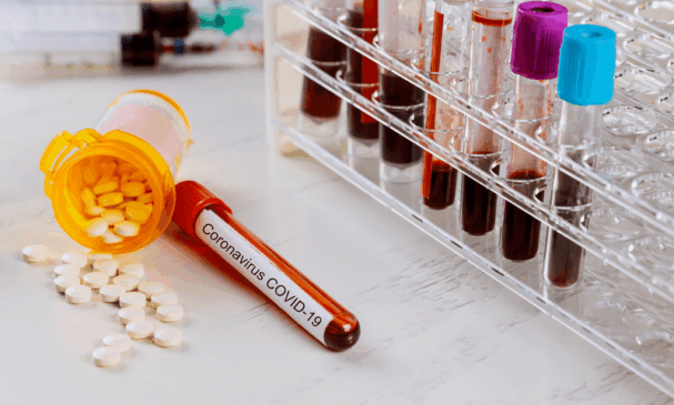 Tubo de ensaio com sangue de paciente com Covid-19 ao lado de medicamento