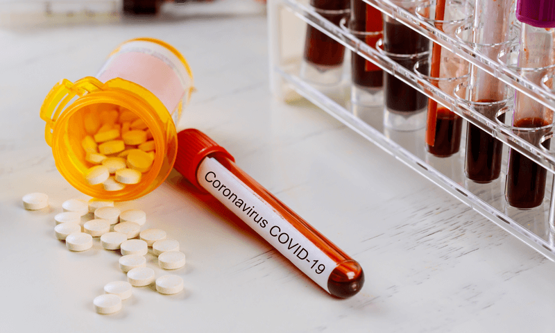 Tubo de ensaio com sangue ao lado de medicamentos