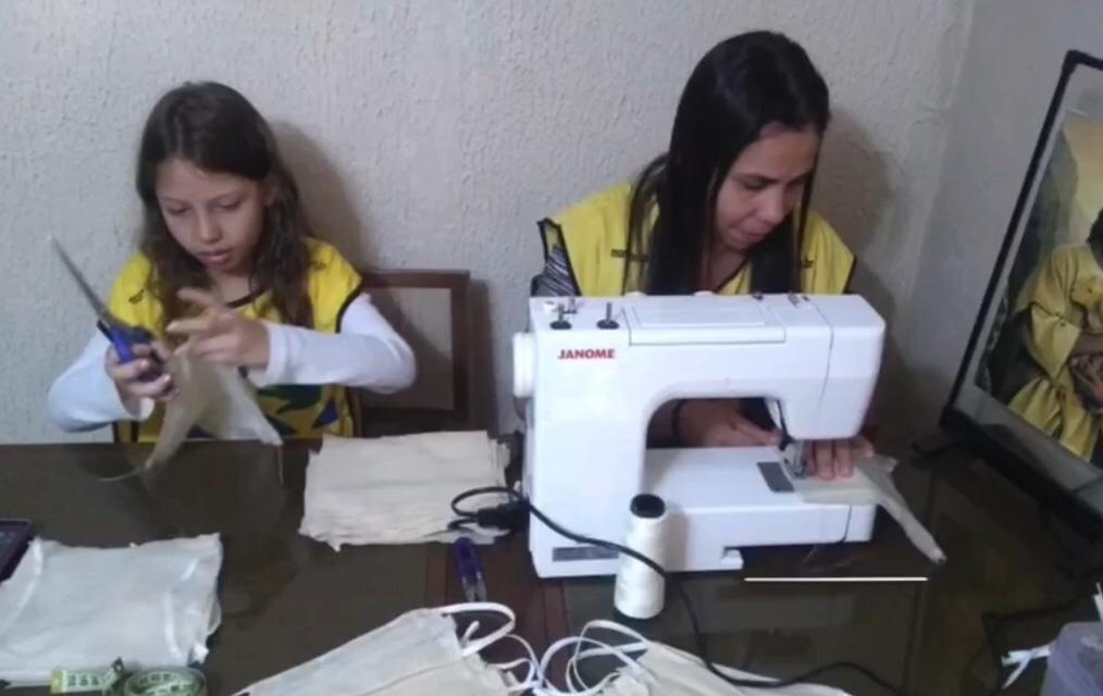 Mulher e criança costurando máscaras
