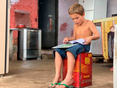 Menino recolhe livros do lixo. (Foto: Divulgação)