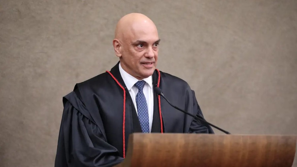 Ministro do STF Alexandre de Moraes falando em púlpito, vestido com toga e gravata.