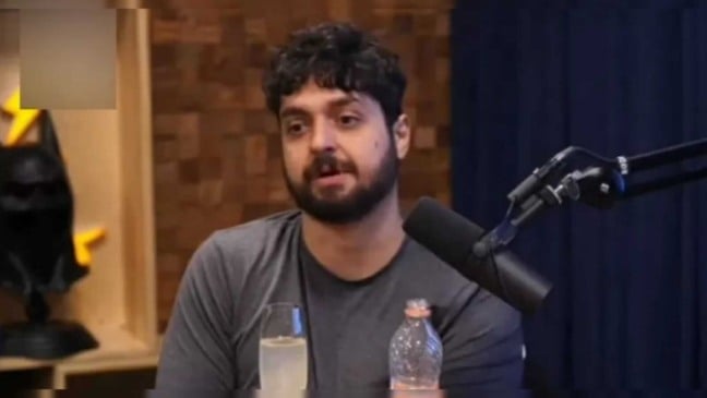 Mornak, podcaster senatado na frente de um microfone no podcast "Flow"