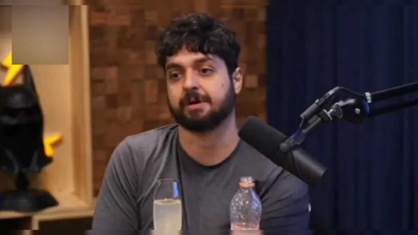 Mornak, podcaster senatado na frente de um microfone no podcast 