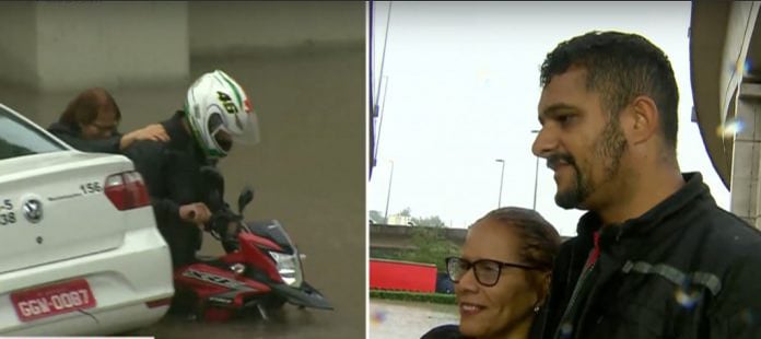 duas pessoas sendo socorridas de um alagamento por um motociclista em são paulo