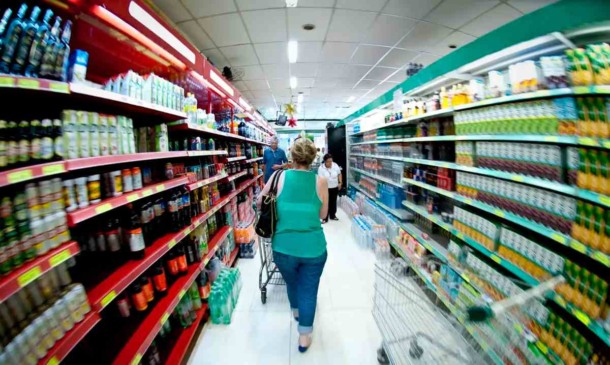 Mulher fazendo compras em corredor de supermercado, simbolizando o impacto da inflação no custo dos alimentos para famílias.