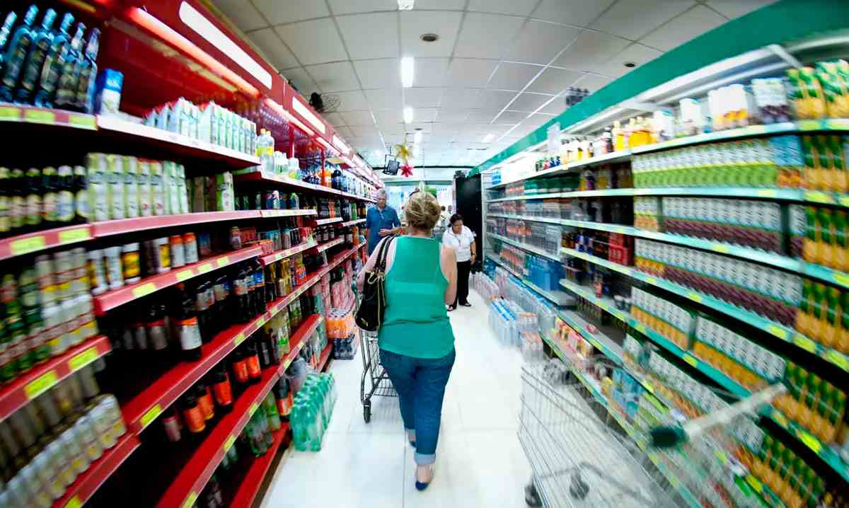 Mulher fazendo compras em corredor de supermercado, simbolizando o impacto da inflação no custo dos alimentos para famílias. Mulher fazendo compras em corredor de supermercado, simbolizando o impacto da inflação no custo dos alimentos para famílias.