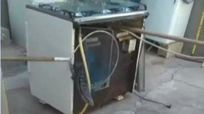 Agentes da Defesa Civil de Várzea Paulista retirando um lagarto encontrado dentro de um fogão.