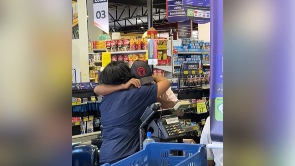 Mulher abraçando homem em caixa de supermercado
