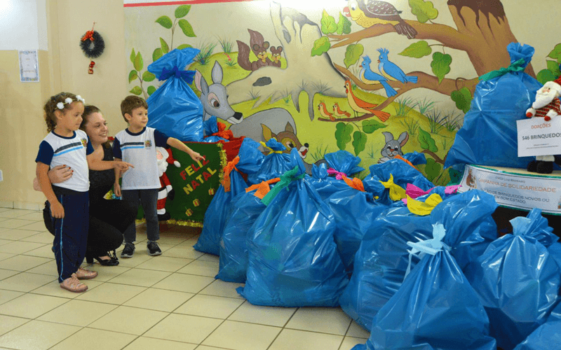 Duas crianças e professora observam montante arrecadado