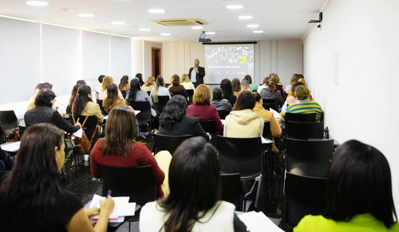 Reunião do Núcleo de Mulheres na ACE Jundiaí, com participantes em sala assistindo a uma apresentação em tela projetada.