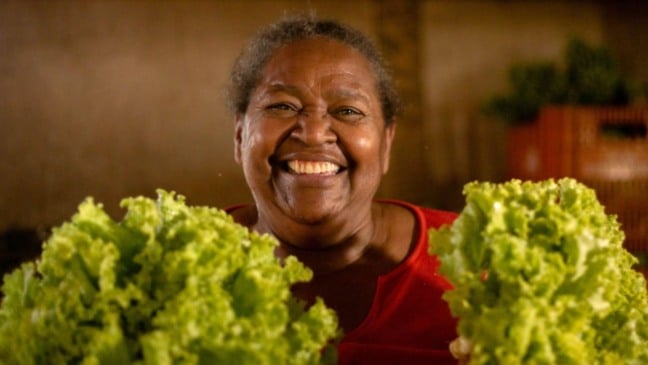 Mulher segurando pés de alface