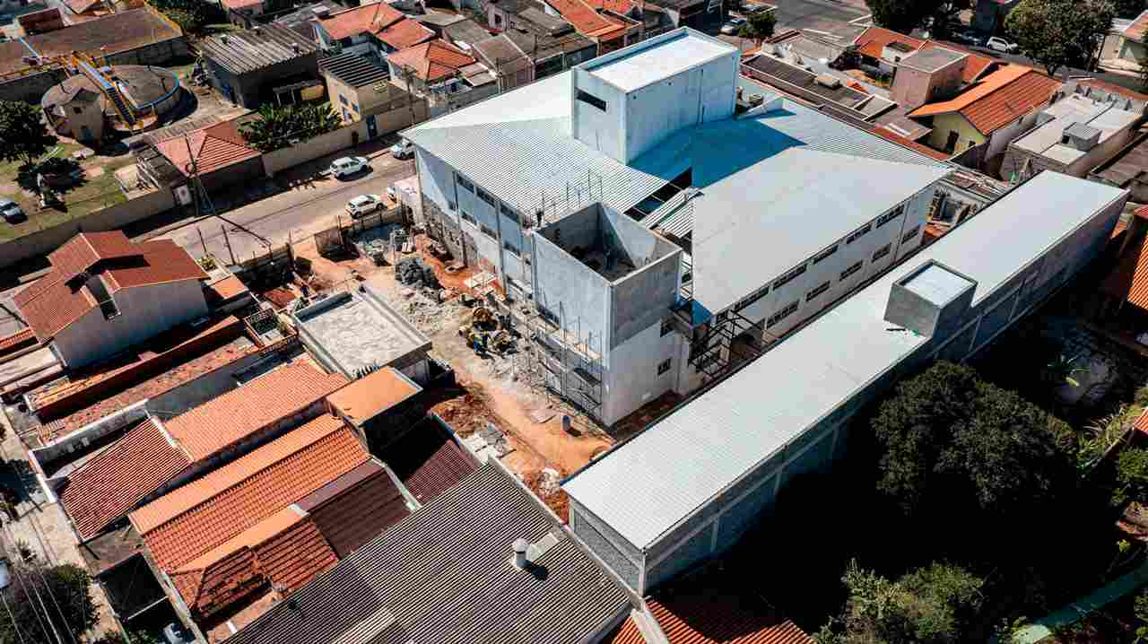 Vista aérea de obras em Jundiaí, mostrando construção de grande edifício em bairro residencial com telhados vermelhos.
