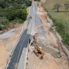 Vista aérea das obras de duplicação da Serrinha em Cabreúva, com trecho asfaltado, máquinas escavadeiras e trabalhadores em atividade na rodovia.