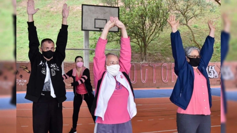 Três pessoas fazendo alongamento em uma quadra