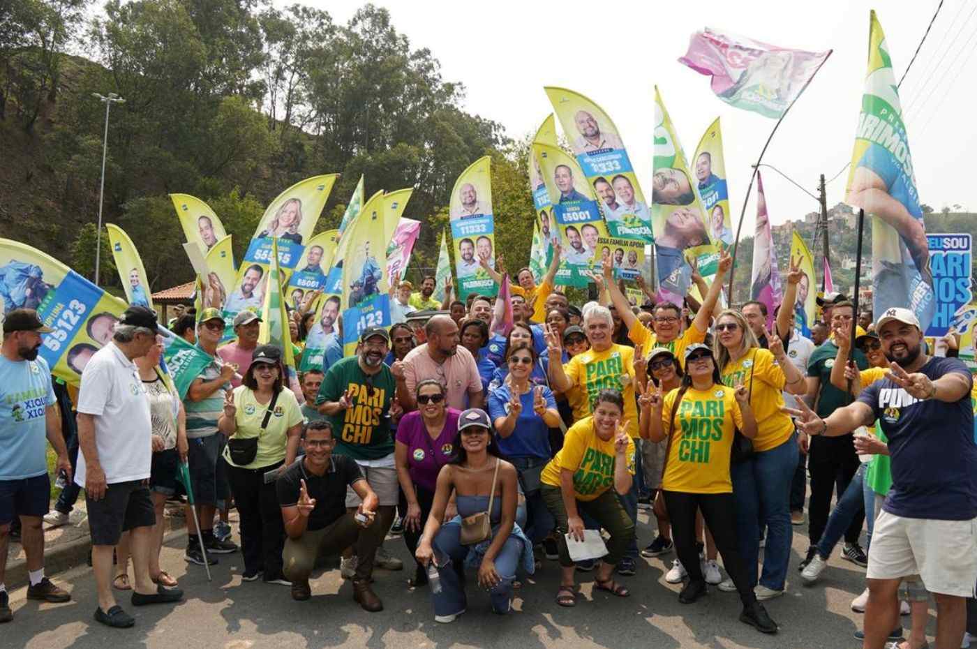Apoiadores de Parimoschi e Albino se reúnem em evento de campanha no Jardim Tamoio, Jundiaí, segurando bandeiras e cartazes eleitorais.