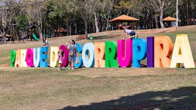 Letreiro colorido “Parque do Corrupira” em Jundiaí com famílias registrando fotos e quiosques revitalizados ao fundo.