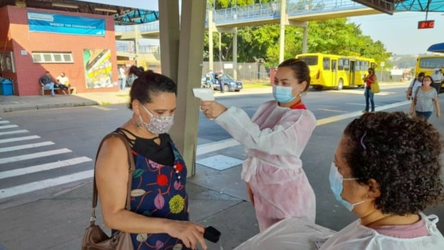 Profissional aferindo temperatura de passageira no Terminal Hortolândia, em Jundiaí