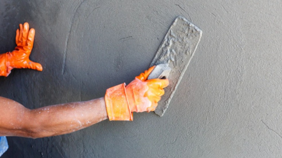 Pedreiro aplicando reboco em parede.