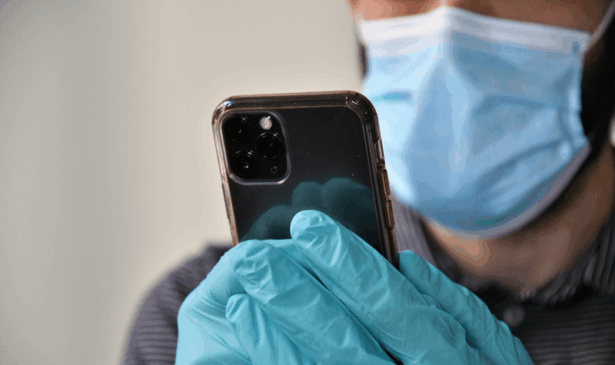 Pessoas com máscara e luva mexe no celular