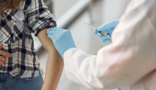 Foto de médico aplicando vacina em mulher