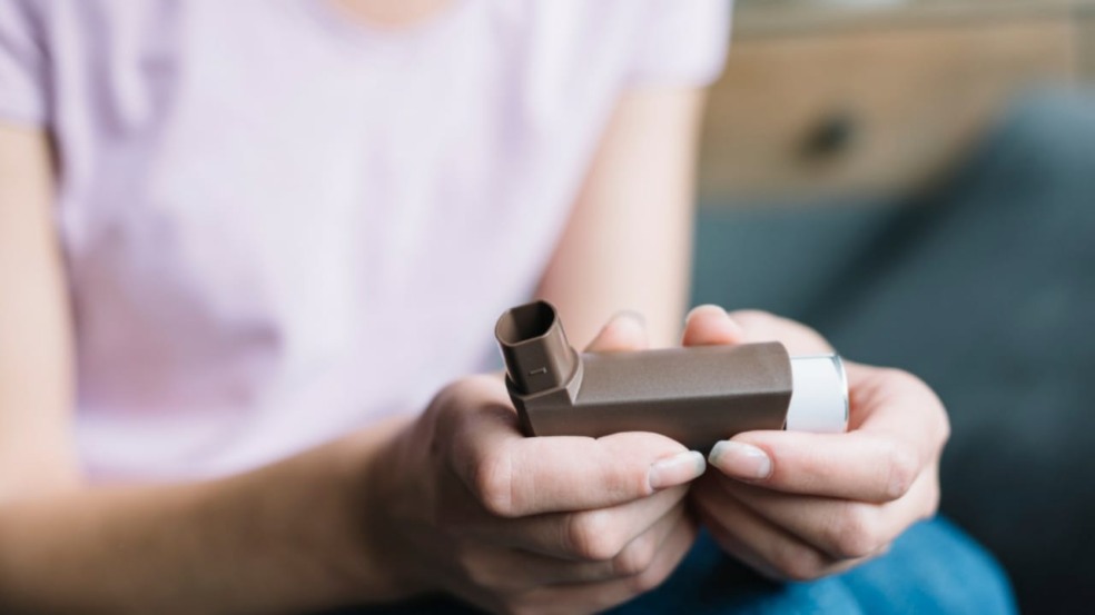 Mulher segurando inalador para asma
