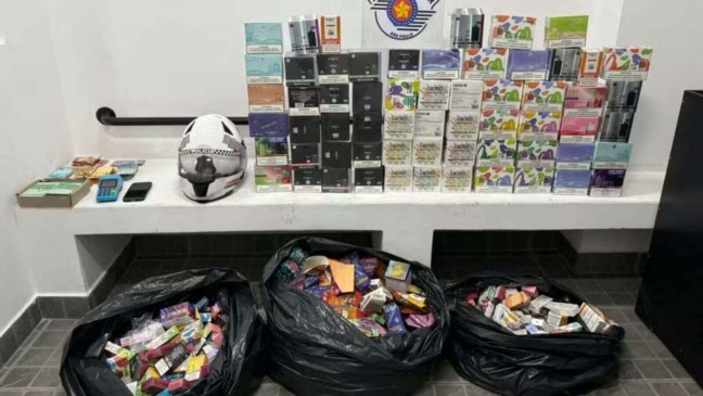 Caixas de cigarros eletrônicos em mesa e em sacos pretos com painel da Polícia de Jundiaí