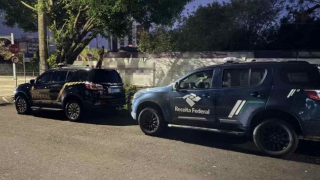 Carros da Polícia Federal e da Receita Federal estacionados lado a lado durante operação.