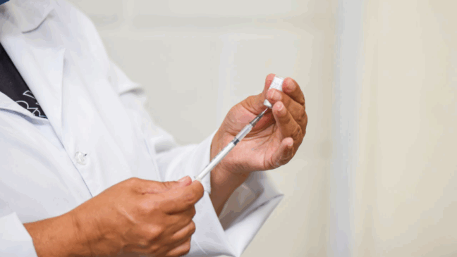 Homem segurando seringa de vacina