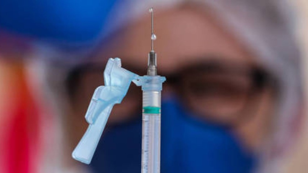 Mulher segurando seringa de vacina