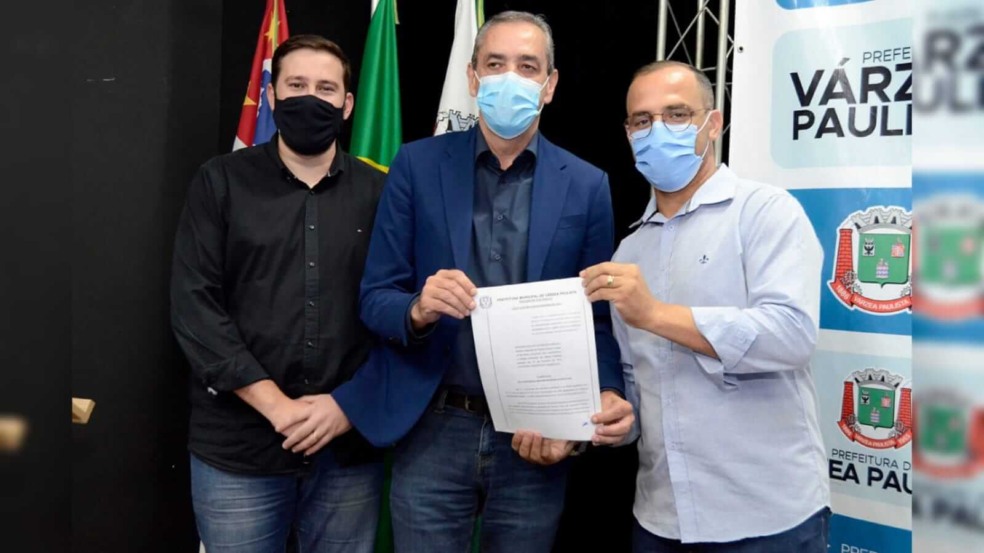 três homens segurando um papel na frente de um painel três homens segurando um papel na frente de um painel