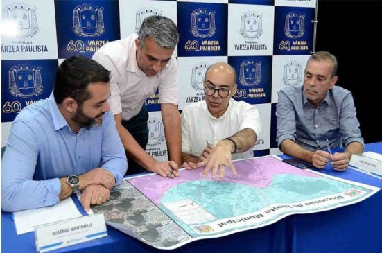 Prefeito Rodolfo Braga e equipe analisam mapa em reunião da Prefeitura de Várzea Paulista, destacando delimitação municipal