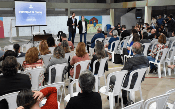 Foto ampla dos participantes sentados em frente ao prefeito Luiz Fernando Machado e vereador Albino