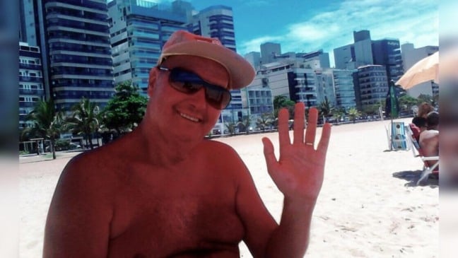 professor Zé Dias na praia acena para a fotografia