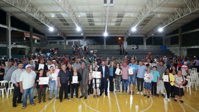 Pessoas segurando a matrícula de imóveis.