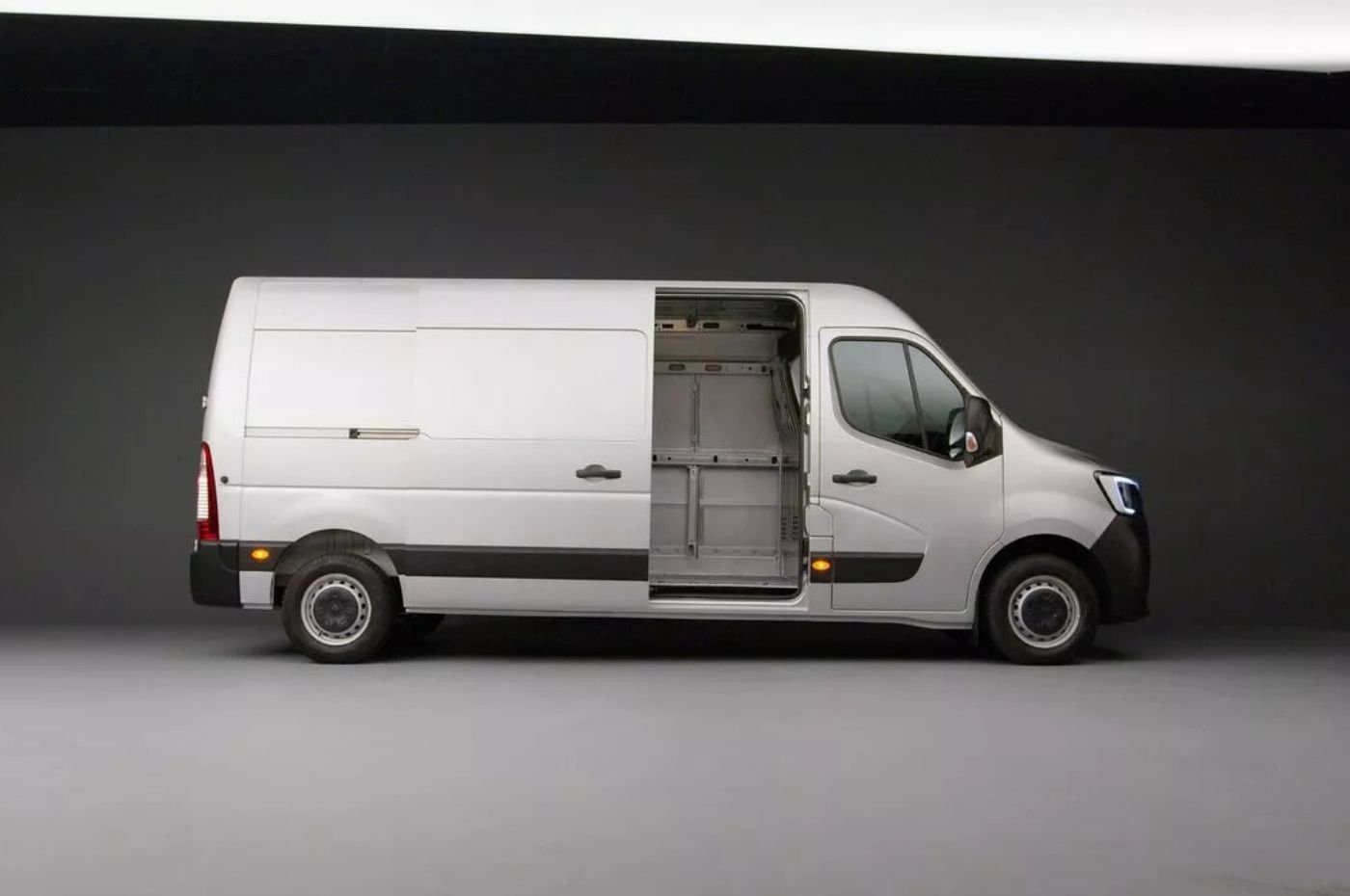 Van Renault Master branca estacionada em área aberta, destacando design frontal moderno com faróis amplos e grade robusta.