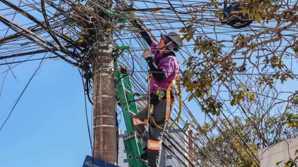 Trabalhador reordenando cabos de telefonia.
