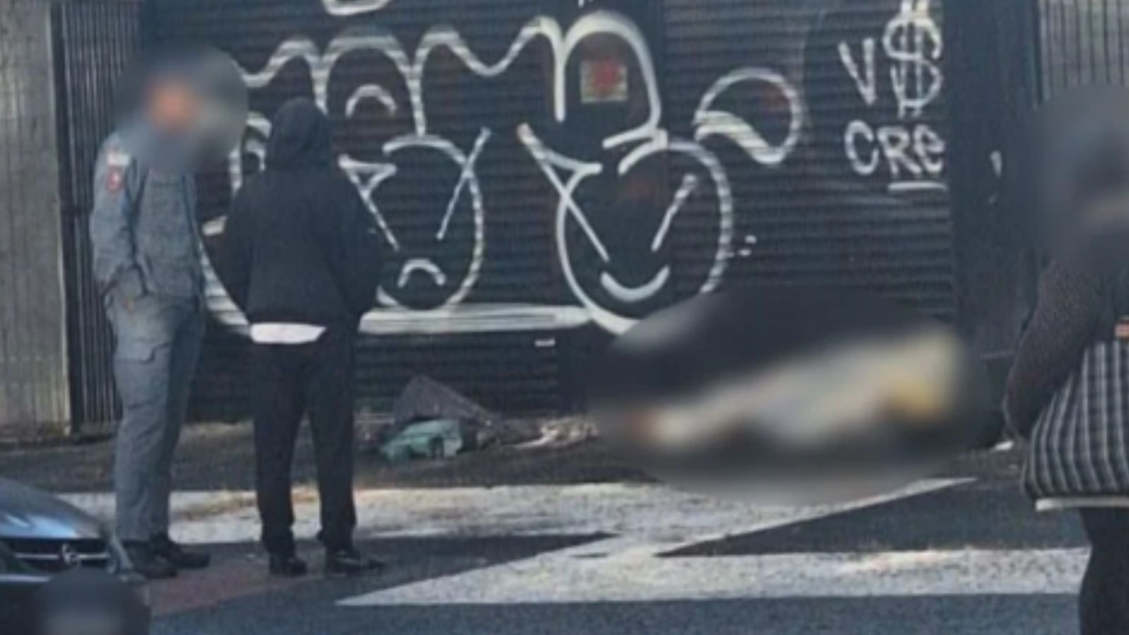 Autoridades ao lado de corpo em calçada.