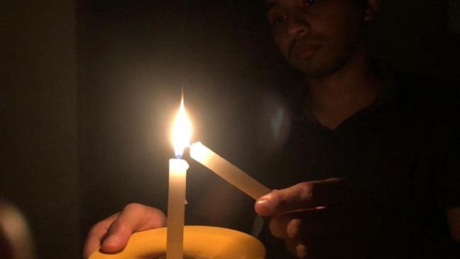 Homem acendendo vela no escuro