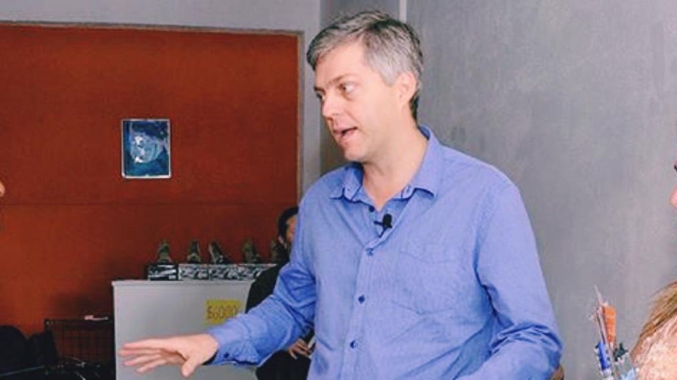 Em pé, Ricardo Benassi conversa com duas pessoas em reunião