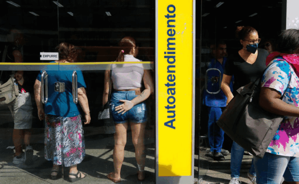 Pessoas dentro de agência bancária perto uma das outras