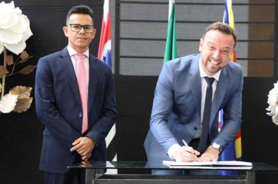 Rogério Cavalin assina posse ao lado de Isaque Messias em cerimônia oficial no Paço Municipal de Itupeva, com bandeiras ao fundo.