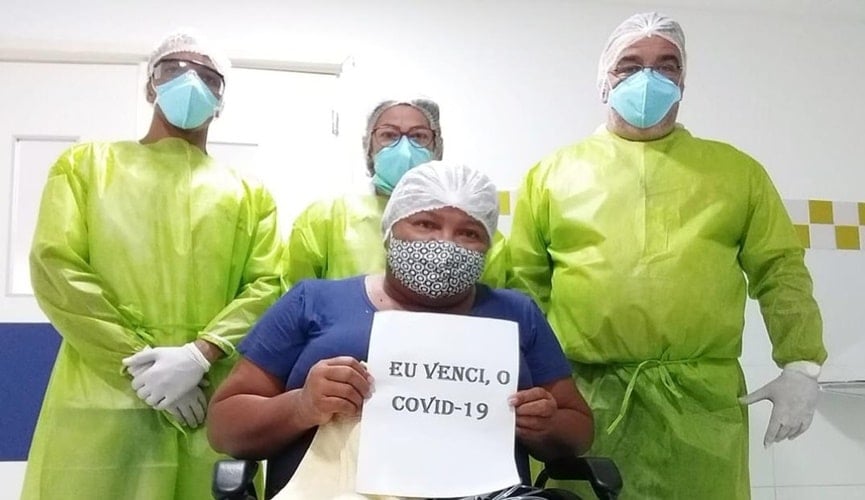 Foto de mulher segurando placa ao lado de enfermeiros