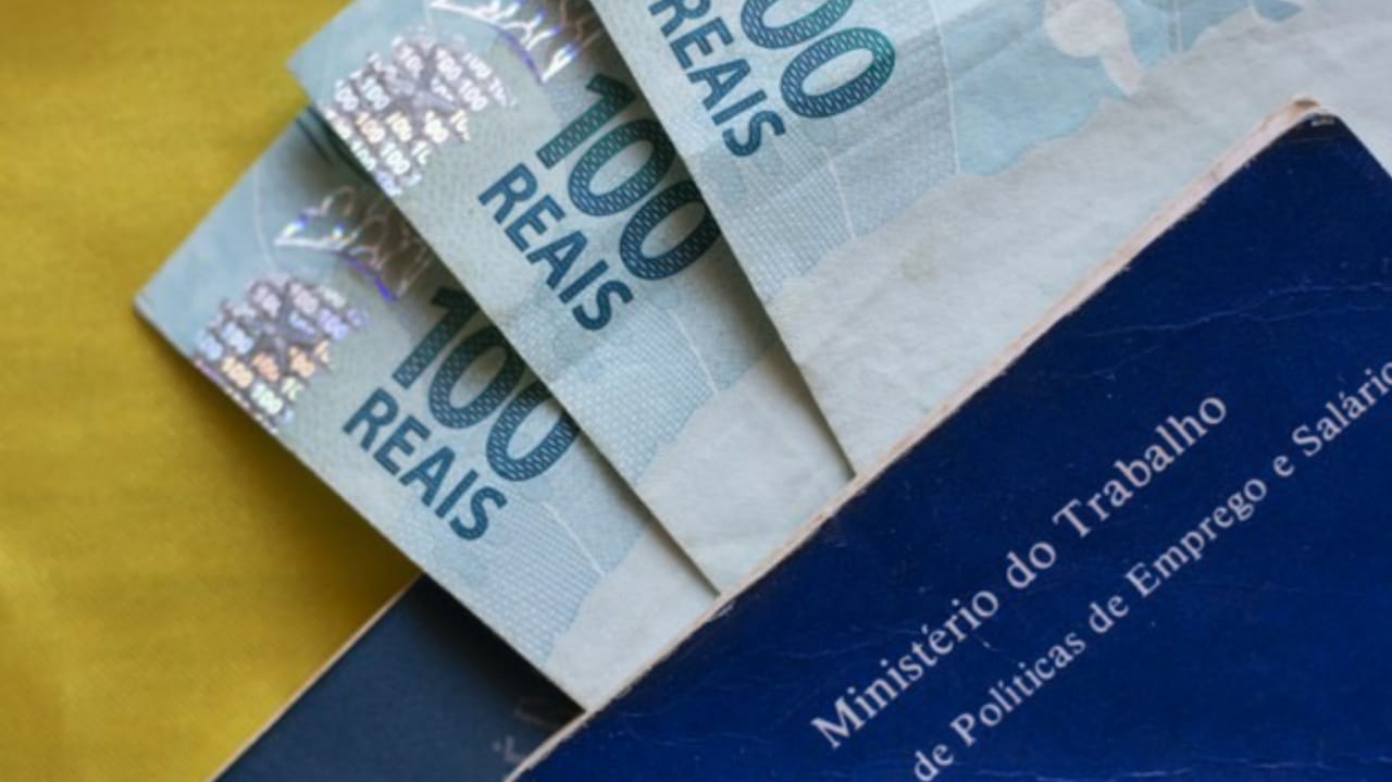 Carteira de trabalho e cédulas de dinheiro