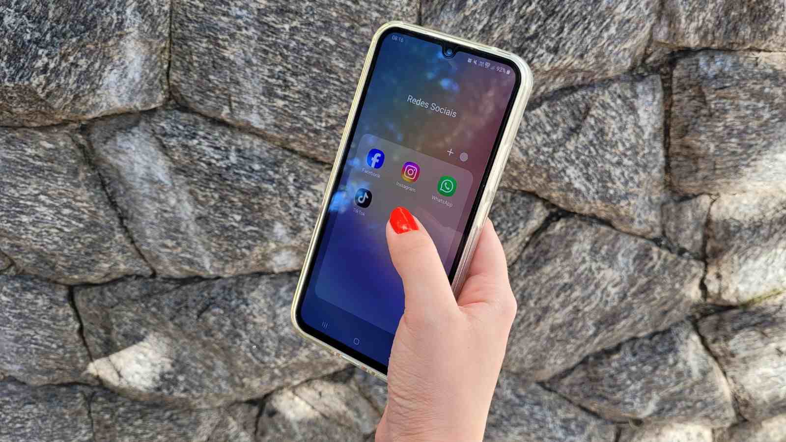 Pessoa segura celular com aplicativos de redes sociais abertos, simbolizando o uso excessivo de telas e seus impactos na saúde mental.