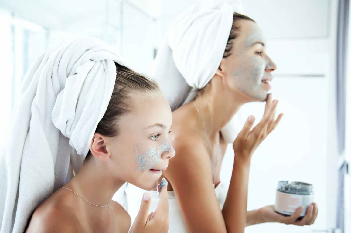 Menina e mulher aplicando máscaras faciais como parte da rotina de skincare em frente ao espelho, simbolizando cuidados com a pele. Menina e mulher aplicando máscaras faciais como parte da rotina de skincare em frente ao espelho, simbolizando cuidados com a pele.