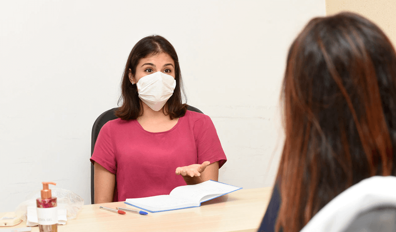 Psicóloga usa máscara e presta atendimento à paciente