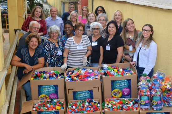 diversas pessoas segurando caixas de papelão com tampinhas de garrafas